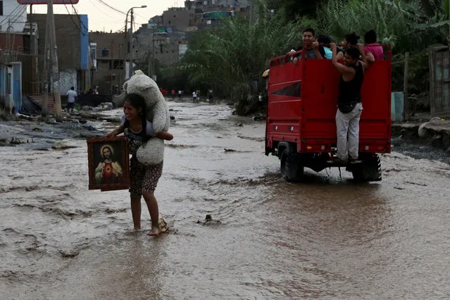 A woman carrying her belongings crosses a flooded street after a massive landslide and flood in the Huachipa district of Lima, Peru, March 17, 2017. (Photo by Guadalupe Pardo/Reuters)