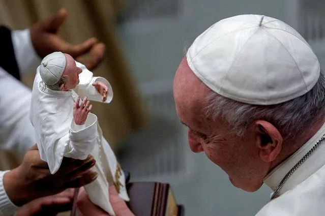 Pope Francis looks at a figurine depicting him held by a woman during the weekly general audience at the Vatican, February 2, 2022. (Photo by Guglielmo Mangiapane/Reuters)