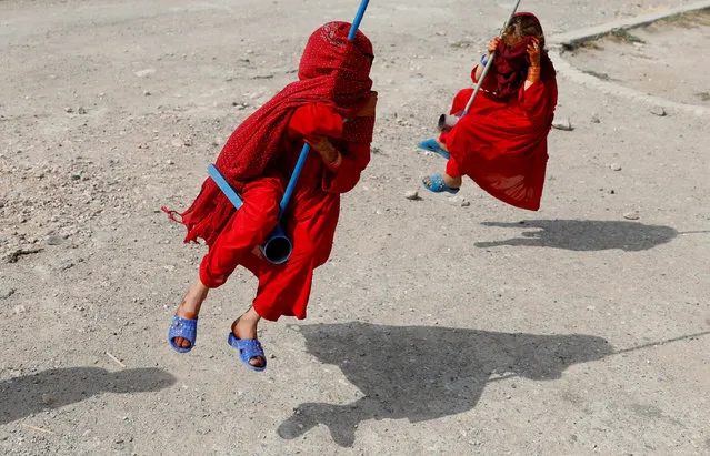 Afghan girls cover their faces as they ride on swings during the first day of the Muslim holiday of the Eid al-Adha, in Kabul, Afghanistan on August 11, 2019. (Photo by Mohammad Ismail/Reuters)