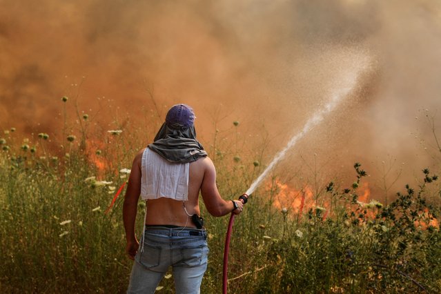 An Israeli man sprays water on fire following rocket attacks from Lebanon, amid ongoing cross-border hostilities between Hezbollah and Israeli forces, in Katzrin in the Israeli-occupied Golan Heights, on June 2, 2024. (Photo by Gil Eliyahu/Reuters)