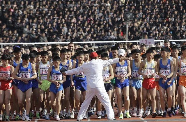 A race official stops eager participants from crossing the starting line prematurely during the Pyongyang marathon on Sunday, April 9, 2017, in Pyongyang, North Korea. (Photo by Wong Maye-E/AP Photo)