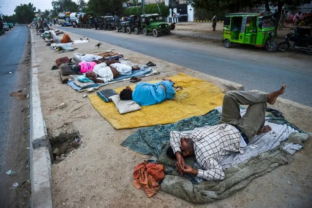 Labourers sleep on a road divider along a street in the port city of Karachi, Pakistan on June 1, 2021. (Photo by Rizwan Tabassum/AFP Photo)