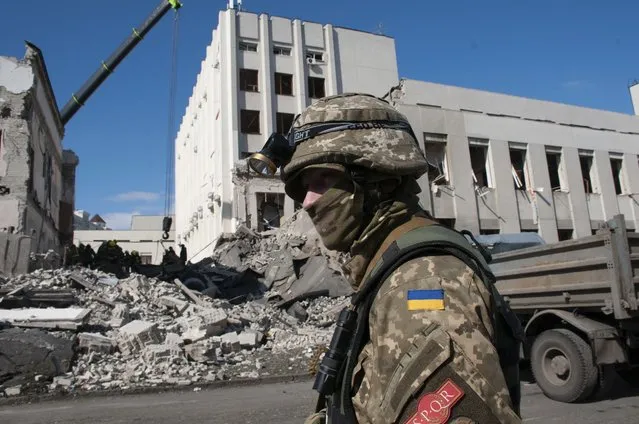 A Ukrainian serviceman guards next to the site of the National Academy of State Administration building damaged by shelling in Kharkiv, Ukraine, Friday, March 18, 2022. (Photo by Andrew Marienko/AP Photo)