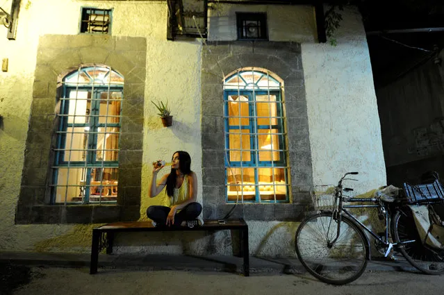 Fine arts graduate Marla Awad, who works at an import and export company, poses for a photograph outside a pub in Old Damascus, Syria on May 18, 2017. “What matters to me was one very negative decision – his refusal to allow the Syrians to immigrate to America in a racist way, because travelling to it was a dream for me to fulfil my ambitions to study and work”, Awad said. (Photo by Omar Sanadiki/Reuters)