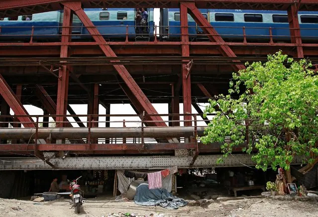 A passenger train makes its way over a bridge above a makeshift cinema in the old quarters of Delhi, India May 25, 2016. (Photo by Cathal McNaughton/Reuters)