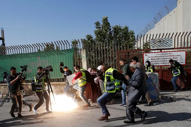 Palestinian journalists react to a stun grenade fired by Israeli forces during a protest to show solidarity with their colleague Muath Amarna, who was shot in his eye, in Bethlehem in the Israeli-occupied West Bank on November 17, 2019. (Photo by Mussa Qawasma/Reuters)