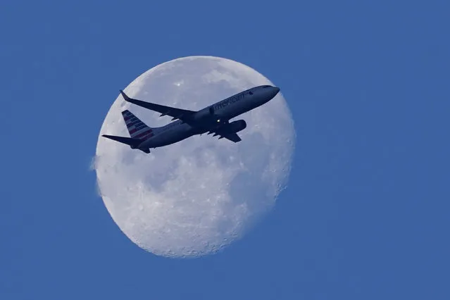 An American Airlines Boeing 737 flies past the moon as it heads to Orlando, Fla., after having taken off from Miami International Airport, Tuesday, April 19, 2022, in Miami. The major airlines and many of the busiest airports rushed to drop their requirements on Monday after a Florida judge struck down the CDC mandate and the Transportation Security Administration announced it wouldn't enforce its 2021 security directive. (Photo by Wilfredo Lee/AP Photo)