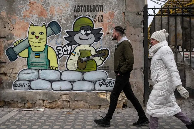 Pedestrians walk in front of a street art creation by the LBWS street art collective on a street in the port city of Odessa on April 13, 2022. (Photo by Ed Jones/AFP Photo)