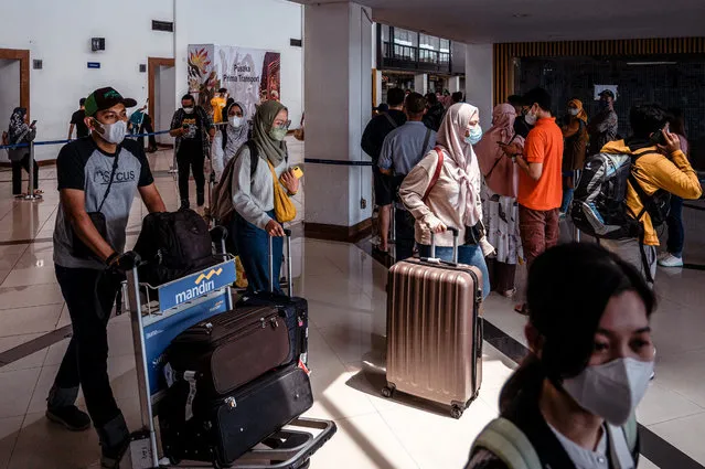 Passengers wait for a flight schedule at Juanda International airport in Sidoarjo on April 29, 2022, as people head to their hometowns ahead of the Eid al-Fitr holiday which marks the end of the holy month of Ramadan. (Photo by Juni Kriswanto/AFP Photo)
