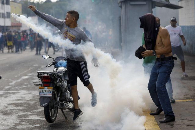 A protester throws a gas canister back at police during demonstrations against the official election results declaring President Nicolas Maduro's reelection, the day after the vote, in Caracas, Venezuela, Monday, July 29, 2024. (Photo by Cristian Hernandez/AP Photo)