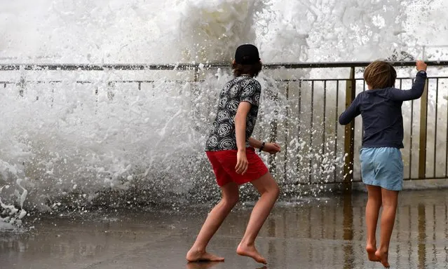 Onlookers watch as large waves pound the promenade and ocean baths at Bronte beach in Sydney on Saturday, April 2, 2022. (Photo by Dean Lewins/AAP)