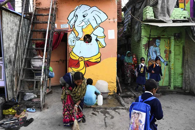 Schoolchildren walk past homes adorned with murals painted by artists from “Delhi Street Art” group at the Raghubir Nagar slum in New Delhi on December 2, 2019. (Photo by Sajjad Hussain/AFP Photo)
