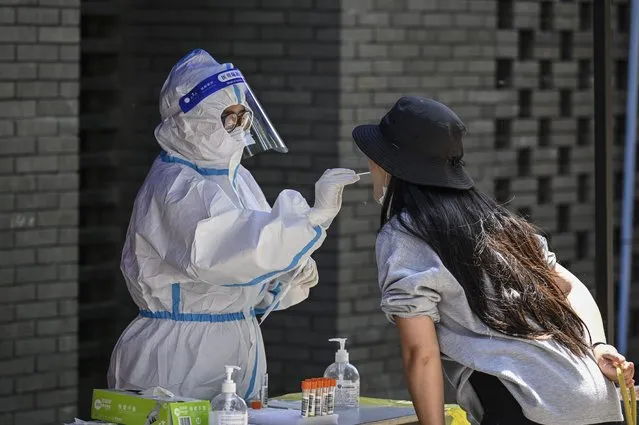 A health worker takes a swab sample from a woman to be tested for the Covid-19 coronavirus at a makeshift testing site in Beijing on May 14, 2022. (Photo by Jade Gao/AFP Photo)