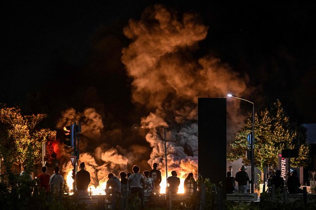 People look at burning tyres blocking a street in Bordeaux, south-western France on late June 29, 2023, during riots and incidents nationwide after the killing of a 17-year-old boy by a police officer's gunshot following a refusal to comply in a western suburb of Paris. (Photo by Philippe Lopez/AFP Photo)