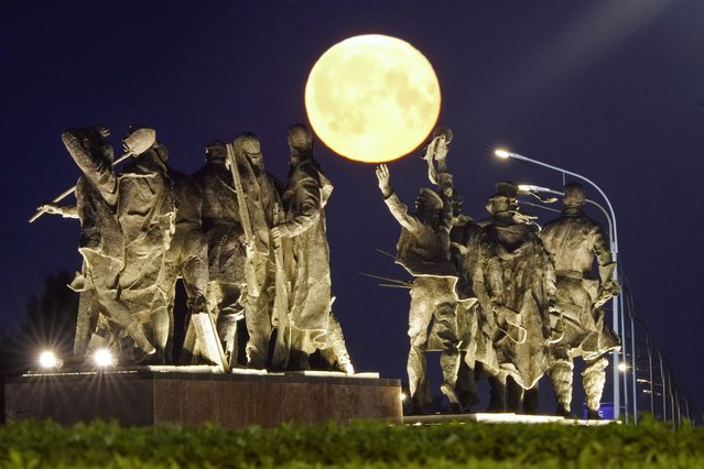 A super moon rises behind a Soviet-era monument for defenders of Leningrad, now St. Petersburg, in World War II, in St. Petersburg, Russia, early Tuesday, July 4, 2023. (Photo by Dmitri Lovetsky/AP Photo)