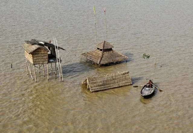 A Sadhu or Hindu holy man rows a boat near submerged huts on the flooded banks of river Ganga after heavy monsoon rains in the northern India caused the rise in water levels, in Allahabad, India, August 11, 2015. (Photo by Jitendra Prakash/Reuters)