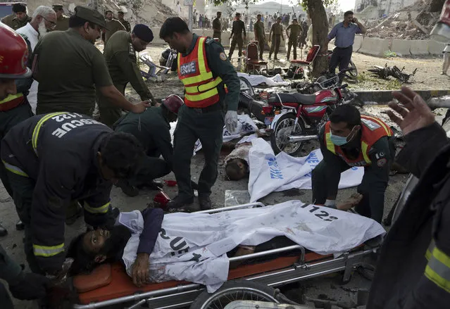 Pakistani rescue workers remove a body from the site of a deadly bombing in the eastern city of Lahore, Pakistan, Monday, July 24, 2017. Pakistani officials said that the suicide motorcycle bombing killed over 20 people and wounded more than 20 others at a vegetable market in the neighborhood of Kot Lakhpat on Lahore's outskirts. (Photo by K.M. Chaudary/AP Photo)