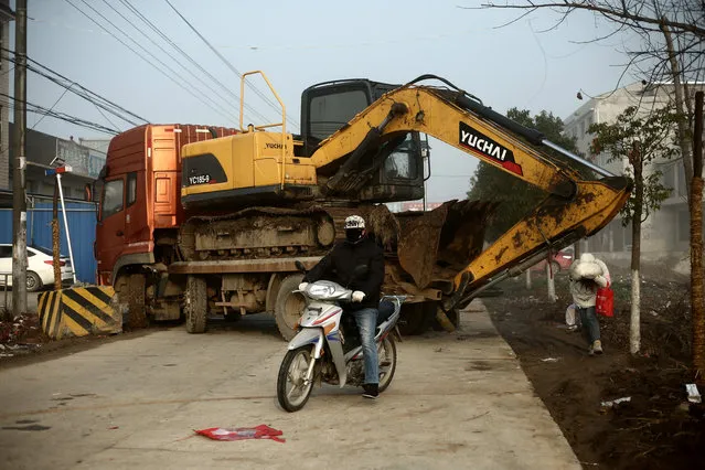 People get around a truck carrying a digger blocking the road to control the virus spread in a small town in Jianli county, Hubei province, China, 28 January 2020. China announced on 27 January that the Spring Festival holiday would be extended to 02 February 2020 after the coronavirus outbreak spread across the country. The virus, which originated in the Chinese city of Wuhan, has so far killed more than 160 people and infected around 6,000, mostly in China. (Photo by Liu Tao/EPA/EFE)