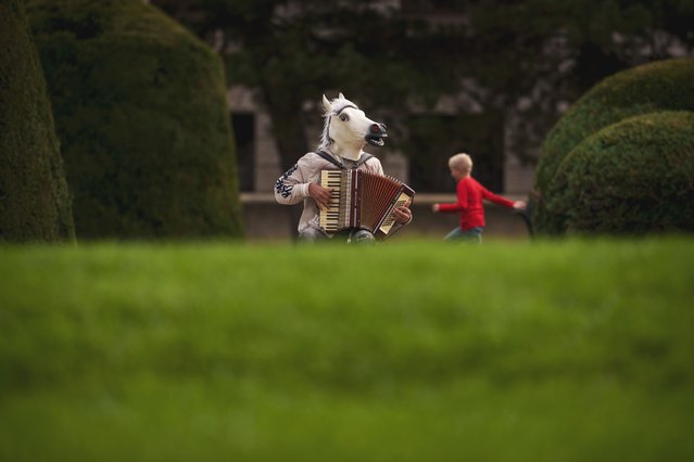 A child runs by a person wearing a horse mask and playing an accordion in the Maria Theresien Platz in Vienna, Austria, Saturday, September 28, 2024. (Photo by Andreea Alexandru/AP Photo)