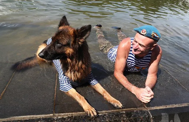 A man and a dog bathe in a fountain during celebrations of Paratroopers' Day in Moscow' s Gorky Park on August 2, 2017. Russia' s Airborne Troops (Blue Berets) celebrate their professional holiday on the Day of Elijah the Prophet, their Patron. (Photo by Stanislav Krasilnikov/TASS)