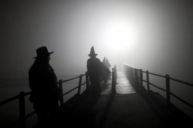 People walk on a footbridge before the opening ceremony of the Witches and Wizards Convention, on Friday the 13th at Paranapiacaba village, in Santo Andre, Brazil on May 13, 2022. (Photo by Amanda Perobelli/Reuters)