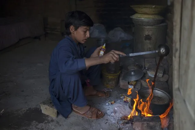 Samiullah, who says he is 14-years-old, prepares tea after finishing work at a coal mine in Choa Saidan Shah, Punjab province, May 5, 2014. (Photo by Sara Farid/Reuters)