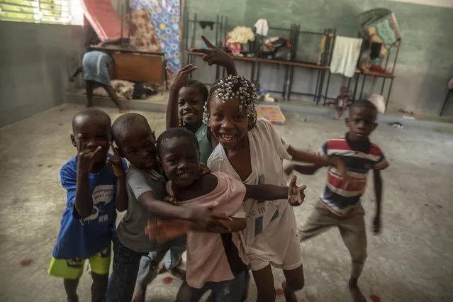 Children forced to leave their homes in Cite Soleil due to clashes between armed gangs, react to a visiting photographer at a school turned into a makeshift shelter in Port-au-Prince, Haiti, Saturday, July 23, 2022. (Photo by Joseph Odelyn/AP Photo)