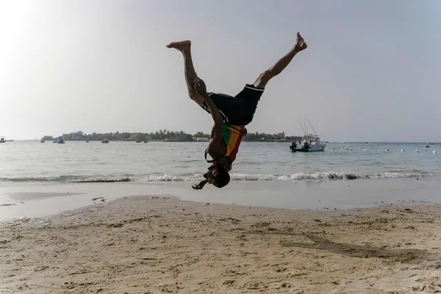 Malick, 30, an acrobat, trains on Ngor beach in Dakar on May 10, 2022. Malick is an acrobat from Guinea who arrived in Senegal in 2015. When he discovered by chance the Sencirk company while living in the street, he started training at the circus tent, then took courses to become a coach. The courses he gives at Sencirk allow him to rent an apartment in Ngor village where he educates young people in the practice of acrobatics. (Photo by Carmen Abd Ali/AFP Photo)