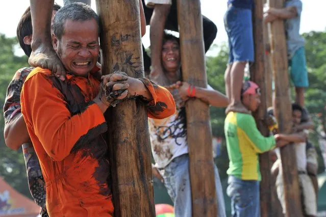 Indonesians participate in a local competition called “panjat pinang” in which people try to climb greased poles that have prizes and flags attached to the top, during an event to celebrate Indonesia's Independence Day in Jakarta on August 17, 2014. (Photo by Adek Berry/AFP Photo)