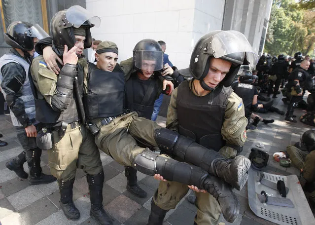 Police officers give medical aid to a colleague after a grenade blast during a clash between protesters and police after vote to give greater powers to the east, outside the Parliament, Kiev, Ukraine, Monday, August 31, 2015. The Ukrainian parliament has given preliminary approval to a controversial constitutional amendment that would provide greater powers to separatist regions in the east. (Photo by Vladimir Donsov/AP Photo)