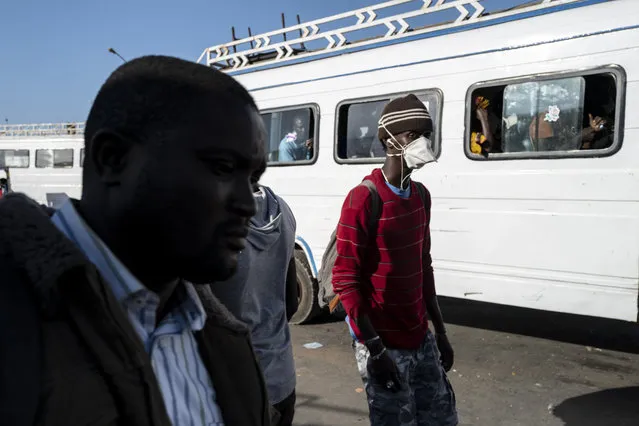 Travelers, some wearing a protective mask, take a bus from the Colobane Bus Station in Dakar, Senegal, Tuesday March 24, 2020. The transport Ministry has announced a limit to the number of passengers to carried in a bus at one time, to prevent the risk of contamination by the Coronavirus. The highly contagious COVID-19 coronavirus can cause mild symptoms, but for some it can cause severe illness including pneumonia that may force admission to hospital. (Photo by Sylvain Cherkaoui/AP Photo)