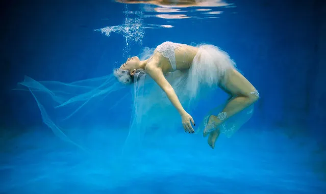 This photo taken on September 3, 2014 shows  Leng Yuting, 26, posing underwater for her wedding pictures at a photo studio in Shanghai, ahead of her wedding next year. Her fiance Riyang said they had their wedding photographs taken underwater because 'its romantic and beautiful'. Mr Wedding studio owner, Tina Lui, started providing underwater pictures four years ago. (Photo by Johannes Eisele/AFP Photo)