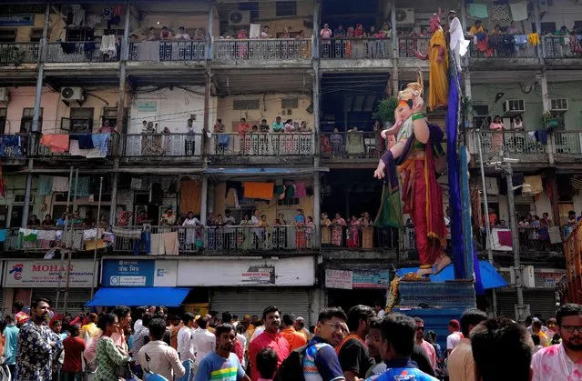 People watch a procession leading an idol of elephant-headed Hindu god Ganesha for immersion during the ten-day long Ganesh Chaturthi festival in Mumbai, India, Friday, September 9, 2022. The festival is a celebration of the birth of Ganesha, the Hindu god of wisdom, prosperity and good fortune. (Photo by Rajanish Kakade/AP Photo)