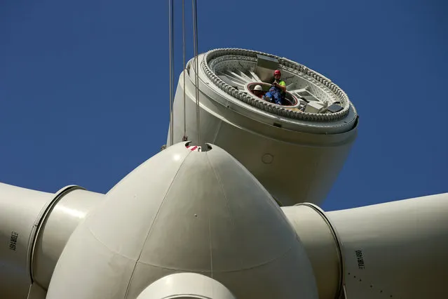 A worker installed in the nacelle looks at the lifting of the rotor hub of a turbine in Meneslies, France July 31, 2014. (Photo by Benoit Tessier/Reuters)