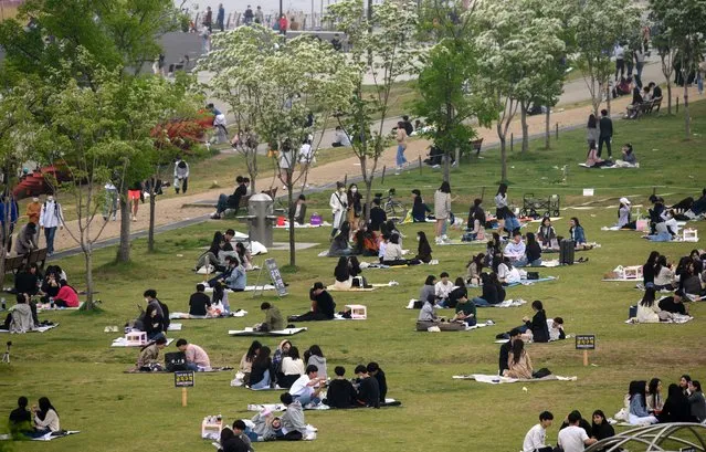 In a photo taken on May 10, 2020, people sit in a park in Seoul. South Korea announced its highest number of new coronavirus cases for more than a month on May 11, driven by an infection cluster in a Seoul nightlife district just as the country loosens restrictions. (Photo by Ed Jones/AFP Photo)
