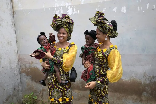 Twins Oladapo Taiwo, left, and Oladapo Kehinde, 21, pose for photographs holding relative's twins during the annual twins festival in Igbo-Ora South west Nigeria, Saturday, October 8, 2022. The town holds the annual festival to celebrate the high number of twins and multiple births. (Photo by Sunday Alamba/AP Photo)