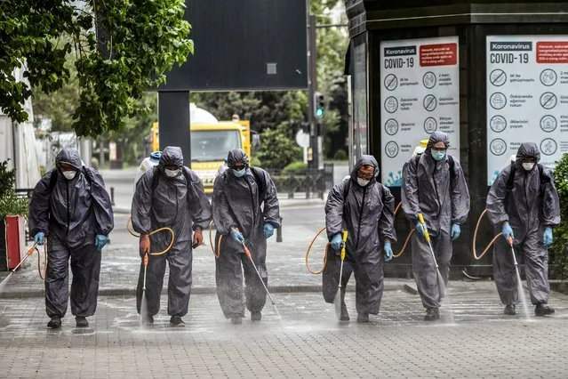 Municipal workers wearing protective suits, amid concerns over the spread of the COVID-19 coronavirus, desinfect a deserted street in Baku on June 21, 2020. Anxiety mingled with anger in Azerbaijan as the Caspian nation reinstated on June 21, 2020 a tight coronavirus lockdown to contain the surge in infections that followed the easing of restrictions weeks ago. Azerbaijanis will now only be allowed to leave home “once a day for a maximum of two hours after receiving permission via text message” from the authorities, Prime Minister Ali Asadov said in a statement. The new measures will remain in force until August 1 in the capital Baku and several other major cities and provinces. (Photo by Tofik Babayev/AFP Photo)