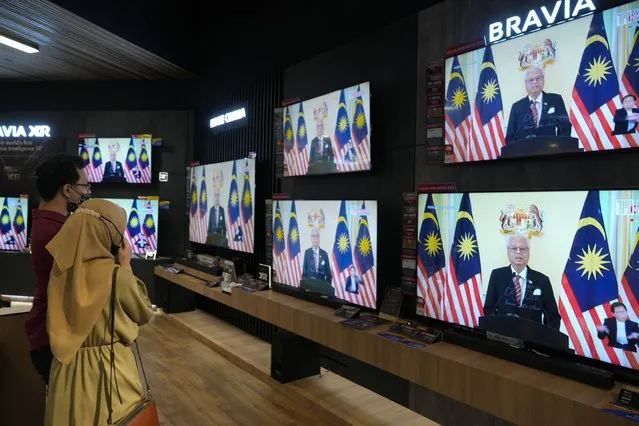 Customers watch a live broadcast of an announcement by Malaysian Prime Minister Ismail Sabri Yaakob at an electronics store in Kuala Lumpur, Monday, October 10, 2022. Ismail announced Monday that Parliament will be dissolved, paving the way for general elections. (Photo by Vincent Thian/AP Photo)