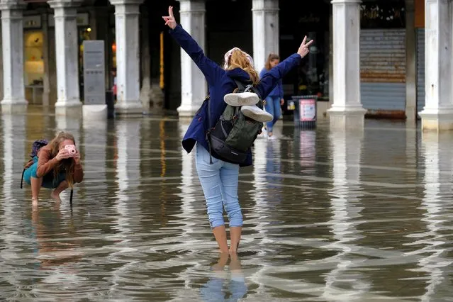 People take photographs in a flooded St. Mark's Square during seasonal high water in Venice, Italy on October 25, 2022. (Photo by Manuel Silvestri/Reuters)