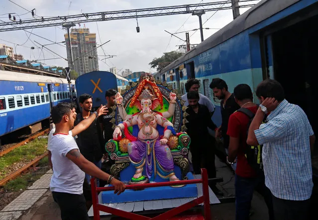 Devotees prepare to load an idol of Hindu elephant god Ganesh, the deity of prosperity, onto a train at a railway station in Mumbai, India August 29, 2016. (Photo by Danish Siddiqui/Reuters)