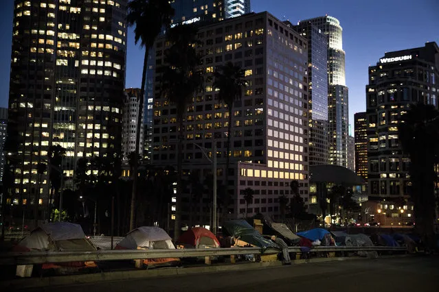 Homeless tents are dwarfed by skyscrapers as 63-year-old Vincent, who only gave his first name, sorts his belongings Friday, December 1, 2017, in Los Angeles. Vincent said he thought he was bulletproof and never had to worry about getting a job as a young man. “Things ain't the way they were anymore”. (Photo by Jae C. Hong/AP Photo)