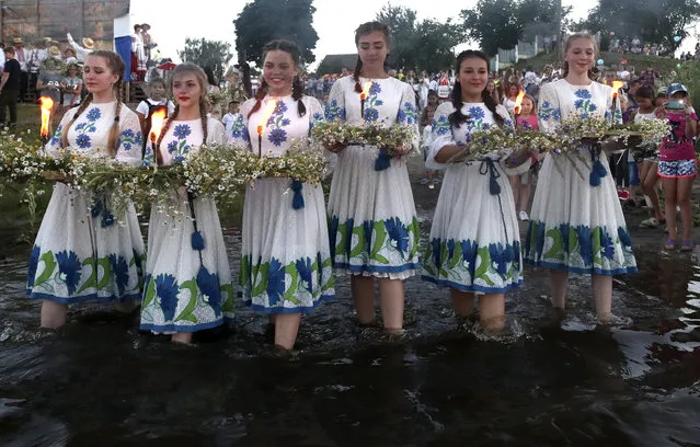 Girls in ethnic costumes carry flower wreaths during Ivan Kupala Day celebrations held by the Pripyat River in the town of Turauin Gomel Region, Belarus on July 6, 2020. (Photo by Natalia Fedosenko/TASS)
