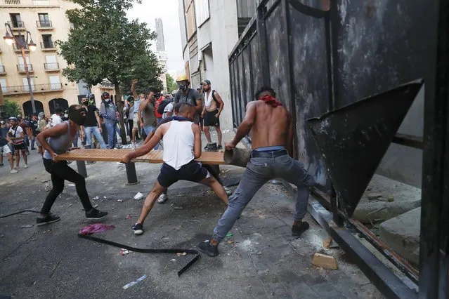 People try to break police barrier during a protest following last week's explosion that killed many and devastated the city, in Beirut, Lebanon, Tuesday, August 11, 2020. The massive explosion of nearly 3,000 tons of ammonium nitrate in Beirut's port killed more than 170 people, injured about 6,000 others and caused widespread damage. (Photo by Hussein Malla/AP Photo)