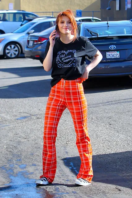 Bella Thorne is all smiles while on the phone as she is seen wearing orange pants and and a black t-shirt in Beverly Hills on December 19, 2017. (Photo by  Splash News and Pictures)