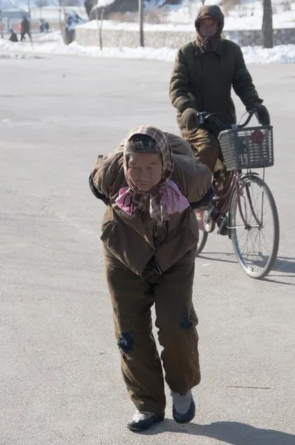 A local struggles with a load on her back in February 2013, in Pyongyang, North Korea. (Photo by Andrew Macleod/Barcroft Media)