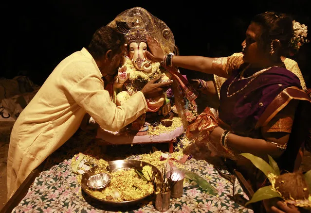 In this Tuesday, September 6, 2016 photo, Raju Laljibhai Dipikar speaks into the ear of an idol of elephant-headed Hindu god Ganesha seeking its blessings as he prepares to make a journey to the Arabian Sea to immerse it, on the second day of Ganesha Chaturthi festival in Mumbai, India. (Photo by Rafiq Maqbool/AP Photo)