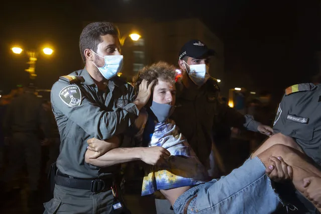 Police carry away a protester as they clear the square outside of Israeli Prime Minister Benjamin Netanyahu's residence in Jerusalem, early Sunday, August 30, 2020. Thousands of Israelis demonstrated in Jerusalem in a continuation of summer-long weekend rallies demanding the resignation of Netanyahu, who faces a corruption trial and accusations of mishandling the coronavirus crisis. (Photo by Maya Alleruzzo/AP Photo)