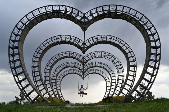 A girl swings on a heart-shaped swing in a park outside Ukrainian capital of Kyiv during warm spring day on April 24, 2025, amid Russian invasion in Ukraine. (Photo by Sergei Supinsky/AFP Photo)