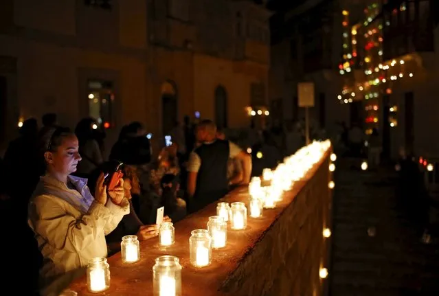 A woman looks at her smartphone during "Birgu by Candlelight" in the medieval city of Birgu, also known as Vittoriosa, outside Valletta, Malta, October 10, 2015. During the annual event, most street lights are switched off and the city is lit up by candlelight, creating a magical ambience, according to its local council. (Photo by Darrin Zammit Lupi/Reuters)
