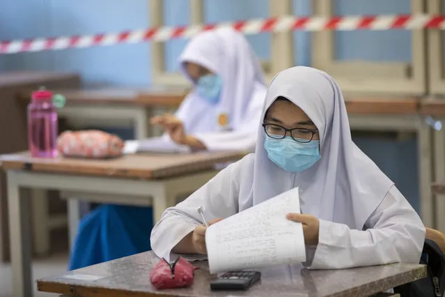 Students wearing face masks and maintaining social distancing at a classroom during the first day of school reopening at a high school in Putrajaya, Malaysia, Wednesday, June 24, 2020. Malaysia began reopening schools Wednesday while entering the Recovery Movement Control Order (RMCO) after three months of coronavirus restrictions. (Photo by Vincent Thian/AP Photo)